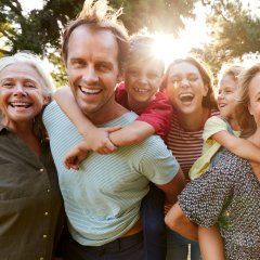Outdoor Portrait Of Multi-Generation Family Walking In Countryside Against Flaring Sun